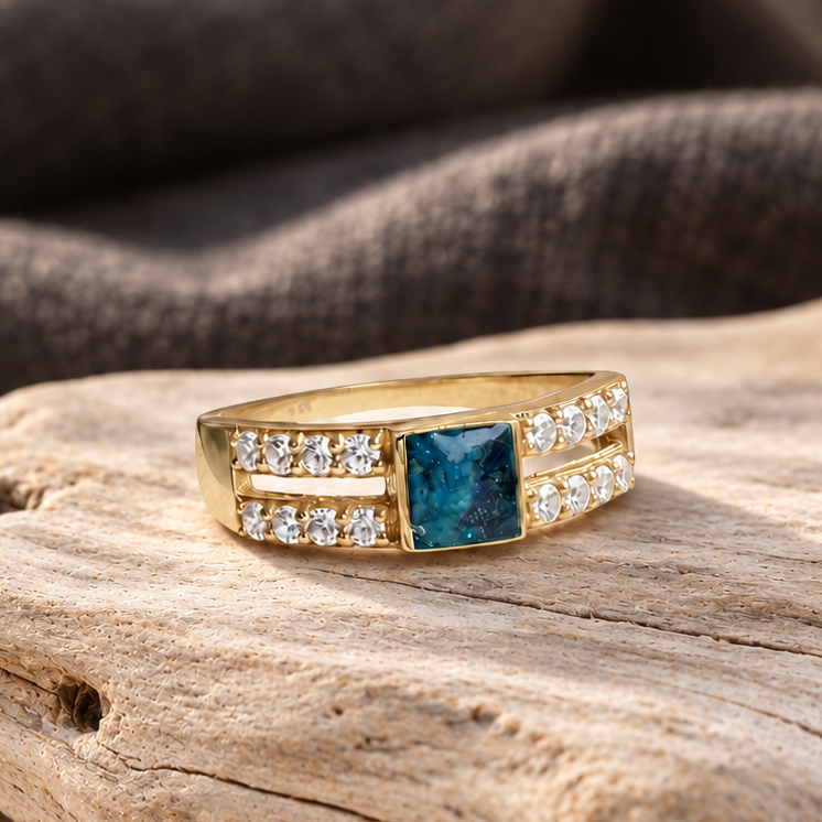 Front view of a gold sentinel Square keepsake ring with visible fabric and two rows of clear accent stones, driftwood.