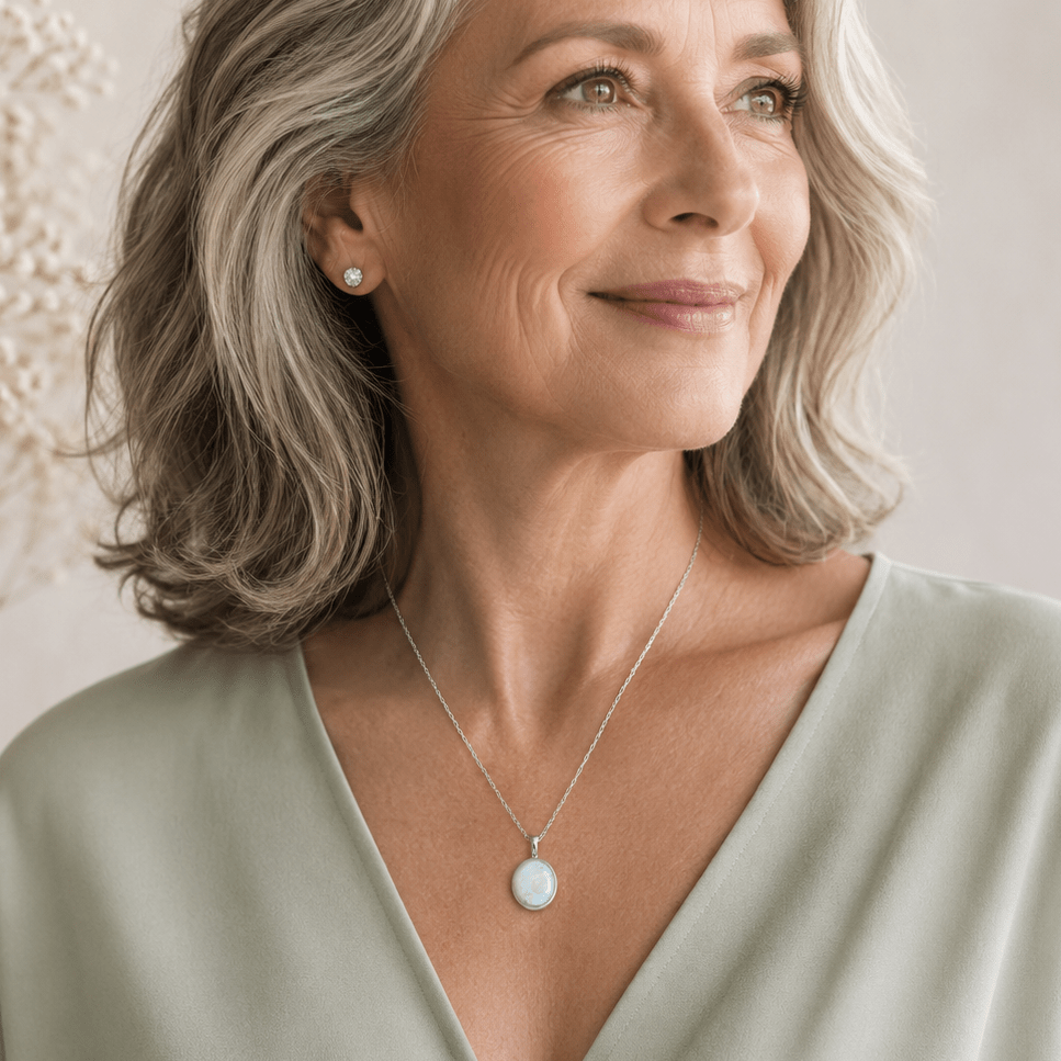 Older woman wearing a solace oval pendant with a white memorial ash stone.